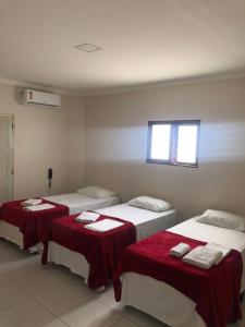 卡鲁阿鲁Prime Hotel的客房设有两张带红色床单的床和窗户。