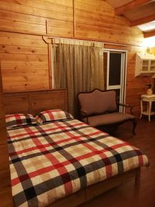 鹿谷乡溪头红瓣天民宿的小屋内一间卧室配有一张床和一把椅子