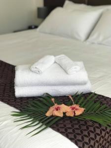阿皮亚The White House Hotel的一间酒店客房,床上摆放着毛巾和鲜花