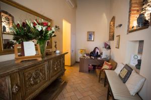 佛罗伦萨伊尔巴杰罗住宿加早餐酒店的坐在桌子上,花瓶满的房间里,女人