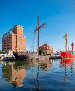 维斯马Appartment im Ohlerich Speicher in Wismar mit Stadt -und Meerblick的坐在建筑物旁边的水中的小船