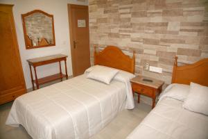 波索阿尔孔Hostal Restaurante Grela的一间卧室配有两张床和镜子