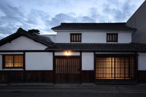 仓敷滔々 御崎 町家の宿 toutou Onzaki Machiya no Yado的一间白色的房子,有黑色的屋顶和两扇门