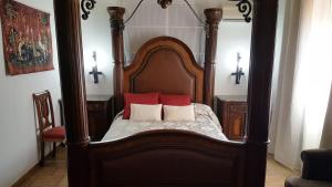 La Calzada de Calatrava奥斯培德里亚酒店的一张带两个红色枕头的木床