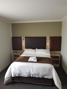 SasolburgBe My Guest Hotel Conference的一间卧室配有一张大床和两个木制床头柜