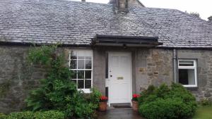 柯克纽顿Highfield Cottage的石屋,有白色的门和窗户