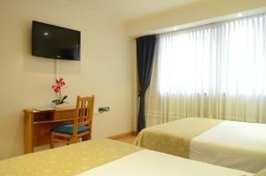 内科切阿Ñikén Hotel & Spa的酒店客房设有两张床、一张桌子和一台电视。