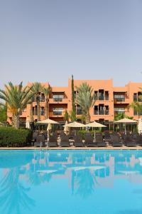 马拉喀什Kenzi Menara Palace & Resort的一个带椅子的游泳池和一个位于酒店后面的酒店