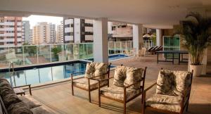 马塞约Apto Promenade I PONTA VERDE的一个带椅子的阳台和一个位于大楼内的游泳池