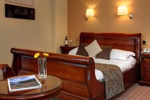 凯西克Lake District Castle Inn的酒店客房,配有一张床和一张带花瓶的桌子