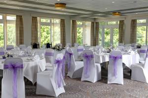 达特茅斯最佳西方达特茅斯高尔夫水疗乡村民宿的一间设有白色桌椅和紫色弓的房间