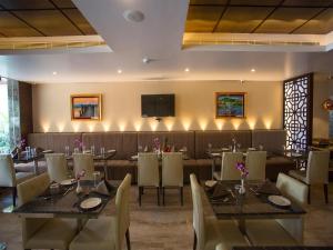 钦奈ST Parklane Airport Hotel Chennai的餐厅设有桌椅和平面电视。