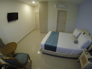 巴兰基亚Hotel Med Centro - Marcari的一间卧室配有一张床、一把椅子和电视