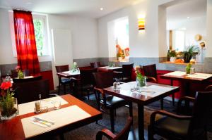 居斯特罗艾姆迪安帕克酒店的餐厅设有木桌和椅子以及红色窗帘