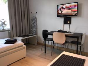 黑尔滕克瑞斯雷克林豪森赫腾公寓的小房间设有一张桌子和墙上的一台电视机