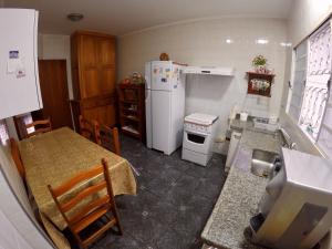 波苏斯-迪卡尔达斯Confortável casa de madeira的厨房配有桌子和白色冰箱。