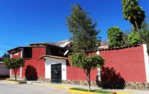 CarhuazCasa Hospedaje"Los Capulies"的一座红白色的建筑,前面有树木
