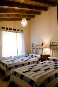 Cabezas AltasCasa rural La Rasa的一间卧室配有两张床和吊灯。
