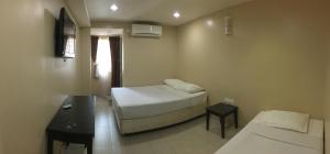 关丹Pantai GuestHouse的小房间设有床、书桌和床筒仓。