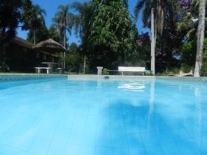 伊比乌纳Hotel Fazenda Bandeirantes的蓝色游泳池,后方设有长凳