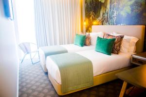 托马尔Thomar Boutique Hotel的酒店的客房 - 带两张带绿色枕头的床