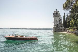 加尔多内-里维耶拉Hotel Villa Fiordaliso的塔楼旁边的水中的小船