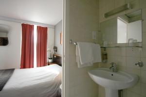 巴黎丹弗特 - 蒙帕纳斯酒店的一间带水槽的浴室和一张位于客房内的床