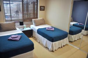 黄金海岸提沃姆斯特民宿的客房设有两张带镜子和紫色毛巾的床。