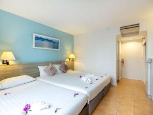 卡伦海滩ON Hotel Phuket - SHA的两张位于酒店客房的床,上面有鲜花