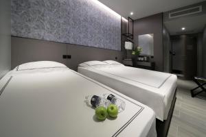 新加坡Hotel Classic by Venue的两张床铺,位于酒店房间,桌子上摆放着绿色苹果