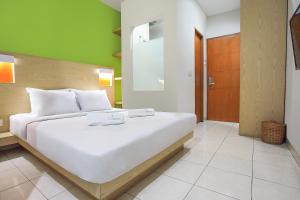 雅加达塞纳扬拉格林套房酒店的卧室设有一张白色大床和绿色的墙壁