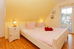 卡尔斯哈根Ahornweg 7a的卧室配有白色床,上面有红色的弓