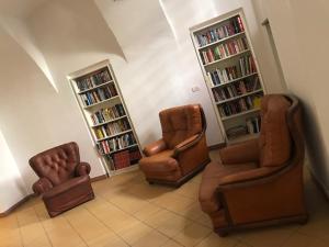 比耶拉Albergo e Ostello della gioventù Biella centro storico的客厅配有3把椅子和书架