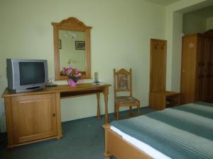 Pilisvörösvár雪绒花旅馆的一间卧室配有一张床和一张书桌及电视