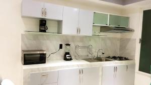 墨西哥城Departamento Privado 3 recamaras的厨房配有白色橱柜、水槽和微波炉
