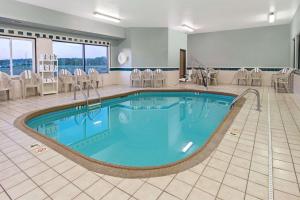 科林斯维尔Days Inn by Wyndham Collinsville St Louis的酒店客房的大型游泳池配有椅子