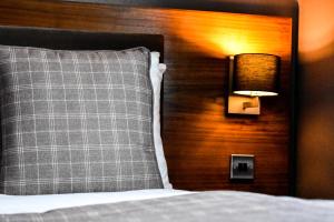 马瑟韦尔丹泽公园酒店 的一张带枕头的床和墙上的灯
