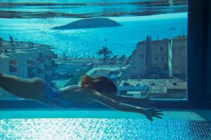 马盖鲁夫INNSiDE by Meliá Calviá Beach的女人在游泳池游泳,欣赏城市美景