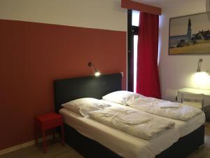 卡尔斯鲁厄Gästehaus Kaiserpassage- Ihr Cityhostel的卧室内的一张床位,卧室设有红色的墙壁