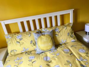 WinfortonThe Sun B&B Rooms的一张带黄色床单和枕头的床,配有Hello枕头