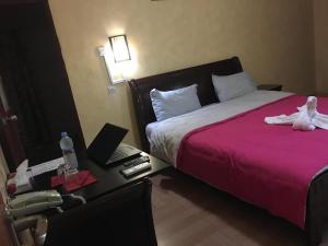努瓦克肖特La Palma Hotel的酒店客房,配有一张带粉红色床罩的床