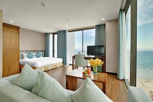 岘港Yarra Ocean Suites Danang的酒店客房配有一张床和一张书桌及一台电视