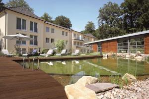 巴特利普施普灵格贝斯特韦斯特尊贵公园Spa酒店的庭院里的一个游泳池,有椅子和一座建筑