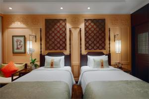会安Little Riverside Hoi An . A Luxury Hotel & Spa的一间客房配有两张床和一张沙发