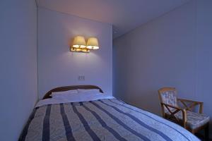 八幡平市Pension Entre - deux - Mers的卧室配有床、椅子和灯