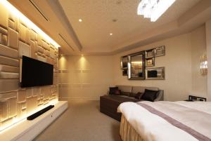 名古屋N Hotel的一间卧室配有一张床、一台电视和一张沙发