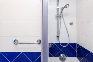 梅塔布鲁村酒店的浴室铺有蓝色和白色瓷砖,设有淋浴。
