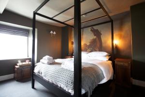 迪德马顿金斯阿姆酒店的一间卧室配有一张天蓬床,墙上挂有绘画作品