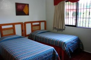 博卡奇卡Hotel Zapata的客房设有两张床和窗户。