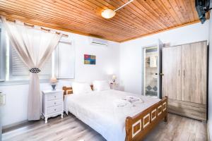 马塔拉Hotel Sofia的卧室设有白色的床和木制天花板。